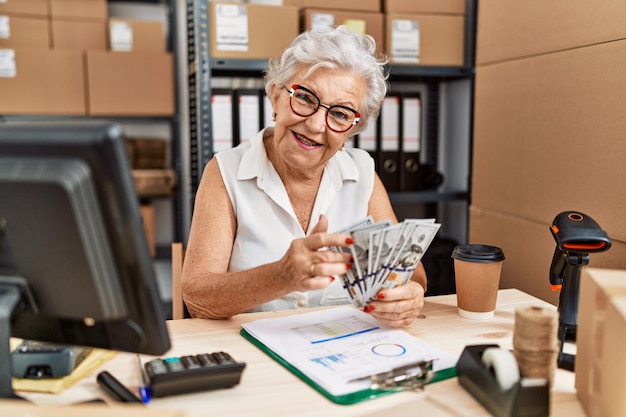 Senior grey-haired woman business worker counting dollars at office