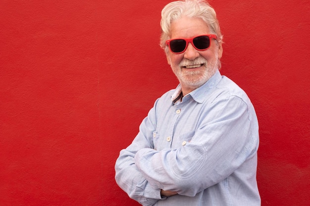 Senior handsome whitehaired man wearing casual shirt over red background with a happy and cool smile on face Lucky person