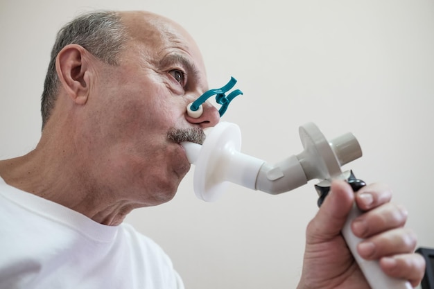 Photo senior hispanic man man testing breathing function by spirometry