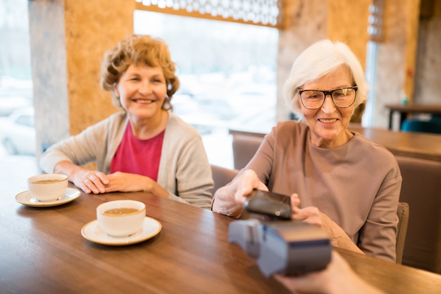 Senior ladies paying with smartphone