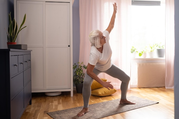 Senior lady doing yoga asana at living room