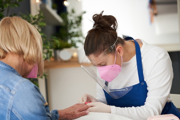 Photo senior lady wearing a mask in manicure salon