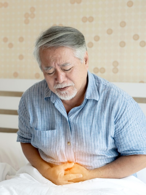 Senior male asian suffering from bad pain in his have a stomachache at home senior healthcare concept