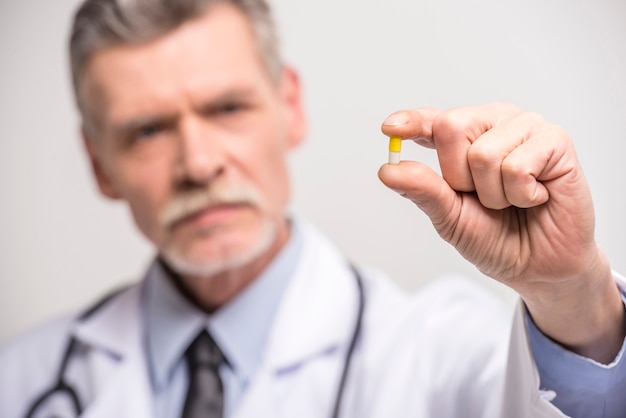 Senior male doctor holding pills