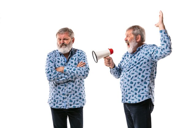 Senior man arguing with himself on white studio background