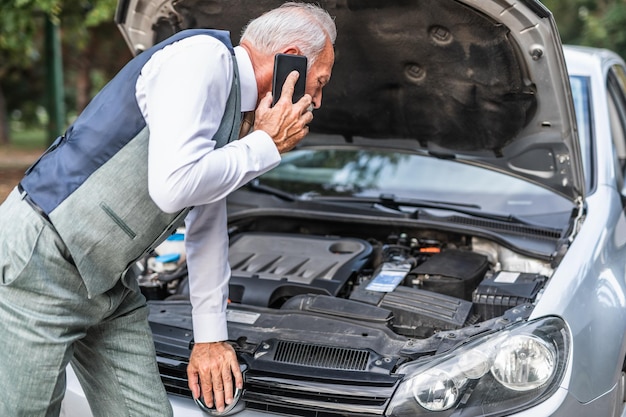 Senior man calling for help after car breakdown.