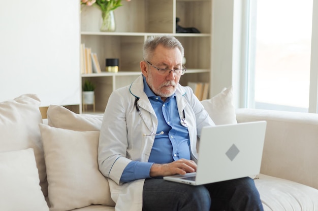 Senior man doctor working with laptop computer professional senior mature healthcare expert searchin