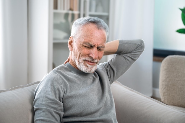 Photo senior man feels severe pain in his neck