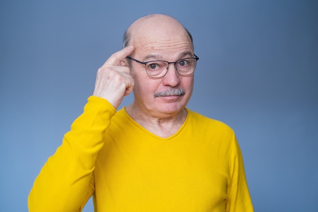 Senior man in glasses holding fingers on his temple