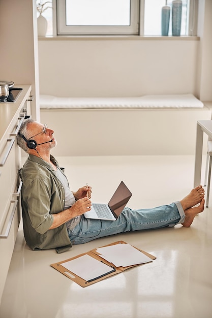 Senior man in headphones and with laptop working form home