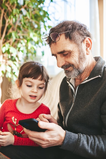 Senior man and his granddaughter using smartphone