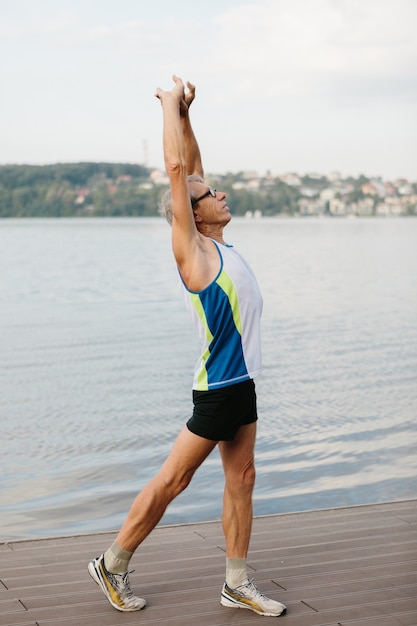 Senior man is engaged in sports on the lake embankment