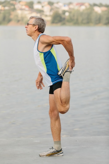 Senior man is engaged in sports on the lake embankment