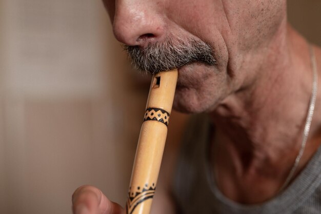 Senior man playing the flute faceless unprofessional male of elderly caucasian recorder people with a moustache with mouth and lips play on pipe amateur music close up at home hobbies and leisure