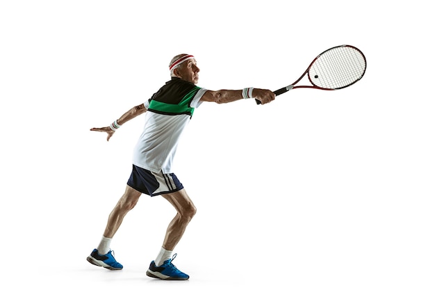 Senior man playing tennis in sportwear isolated on white wall