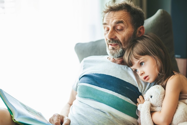 Senior man reading a book to his granddaughter