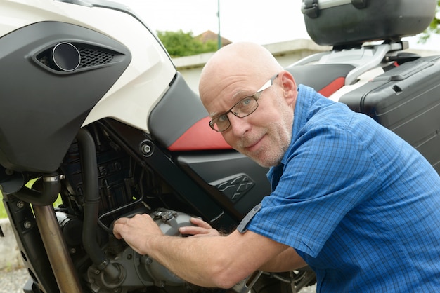 Senior man repairing motorbike outdoor