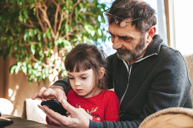 Senior man showing his granddaughter how to use mobile