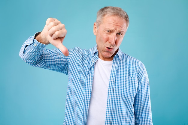 Senior man showing thumbs down sign gesture