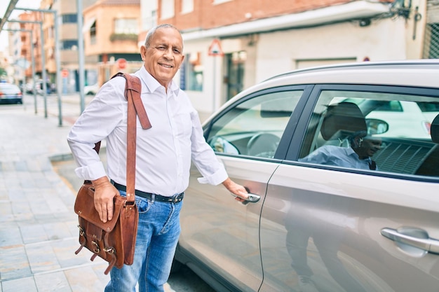 Senior man smiling happy opening car at the city.