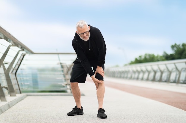 Senior man suffering with knee pain during workout