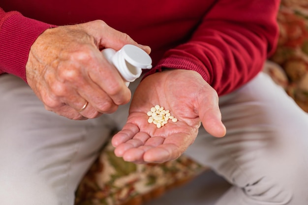 Senior man taking medicine pills supplement closeup of hands