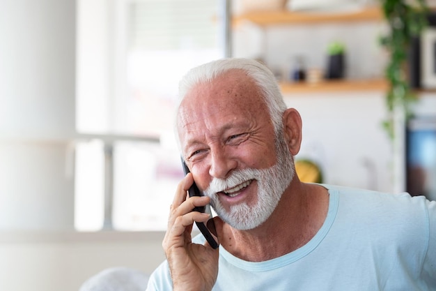 Senior man talking on mobile phone at home Laughing senior man talking on a cellphone while relaxing in a chair in his living room