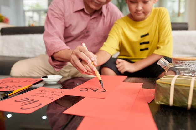 Senior man teaching granson to create greeting cards for chinese new year