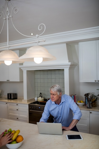 Senior man using interacting while using laptop in kitchen