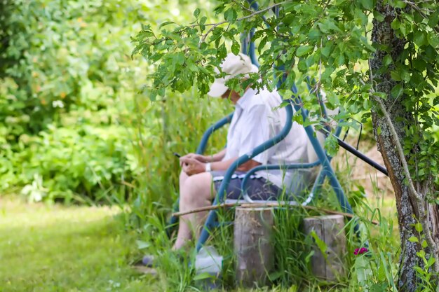 Senior man using smartphone in garden swing