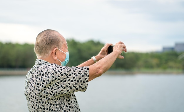 Senior man using smartphone to take photos and video Outrdoor setting