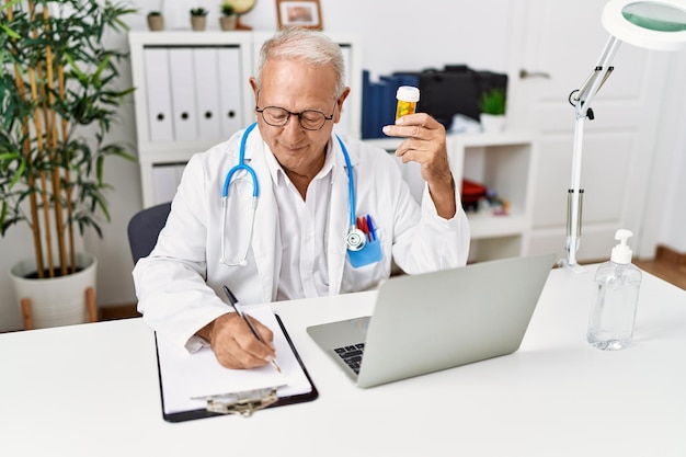 Senior man wearing doctor uniform prescribe pills treatment at clinic