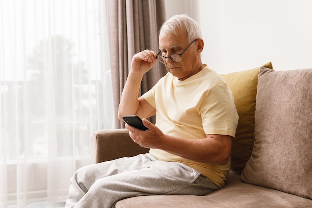 Senior man wearing eyeglasses is using smartphone