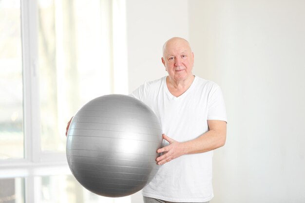 Senior man with fitball in rehabilitation center