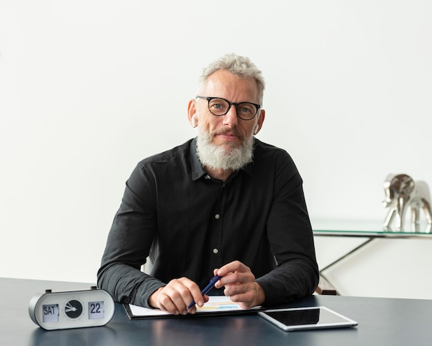 Senior man with glasses at home studying while using tablet