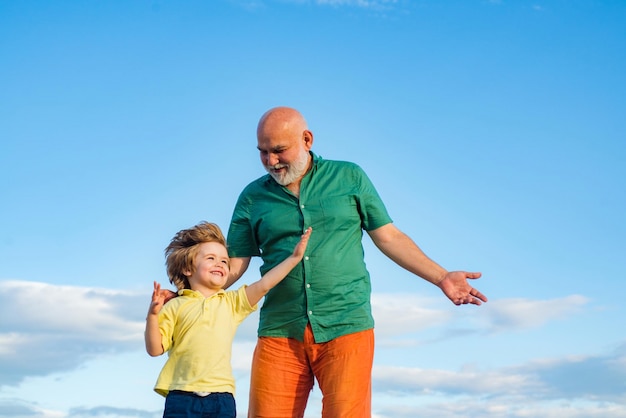 Senior man with grandson jogging in park cute boy with dad playing outdoor grandfather with son in p