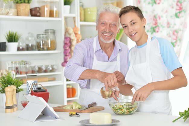 Senior man with grandson preparing dinner in kitchen