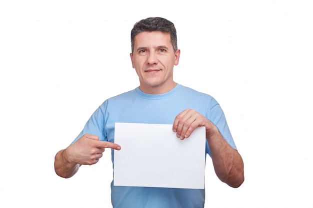 Photo senior man with smiling face holding blank paper and making a gesture pointing his finger at him.