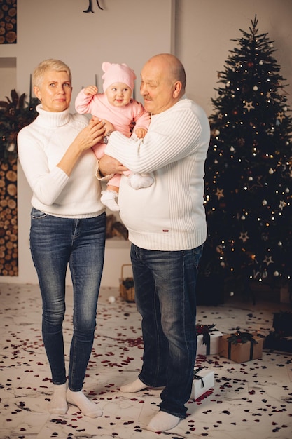 Senior man and woman spending time with little kid on Christmas eve