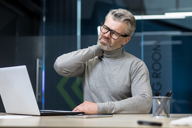 Senior mature businessman working inside office building gray haired man sick and tired massaging