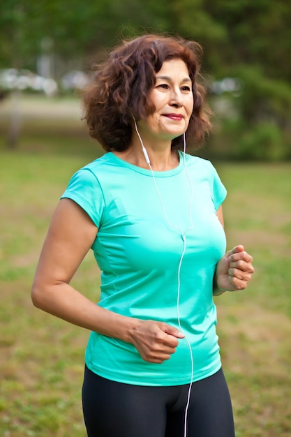 Senior middle age female woman running outdoors in a park