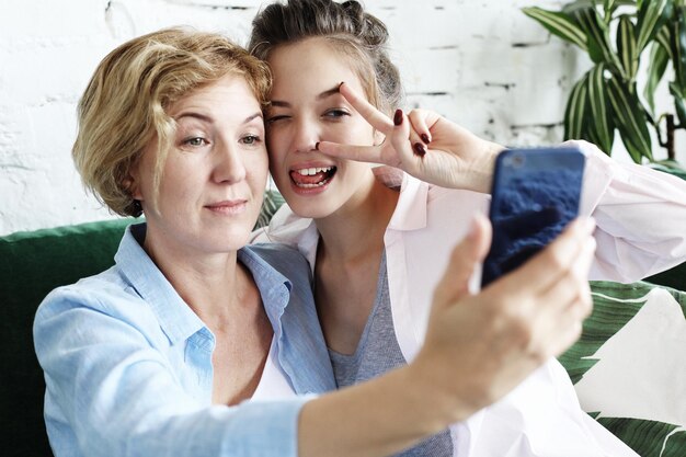 Photo senior mother and her daughter making a selfie using smart phone