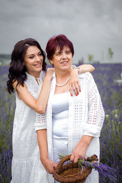 Senior mother with adult daughter walking on the lavender field