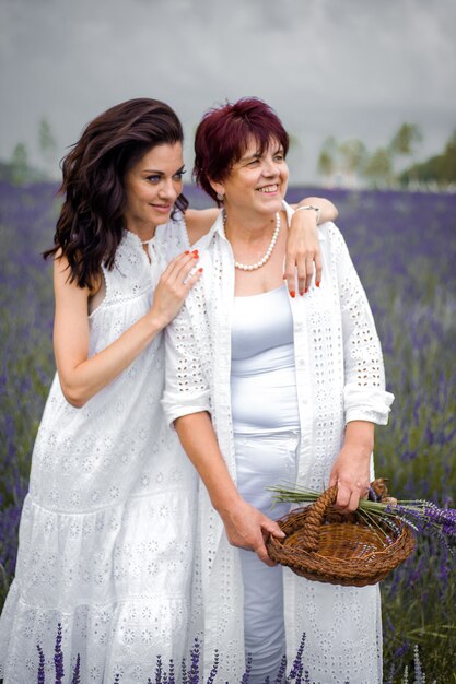 Senior mother with adult daughter walking on the lavender field