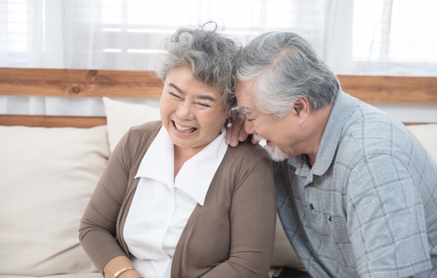 Photo senior old asian couple laugh sit on sofa at home.