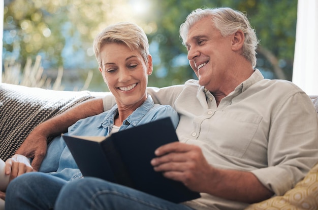 Senior pension and reading couple with a happy smile at home on a lounge sofa Love calm and happiness mindset of a elderly couple with books together looking at pages of a book on a house couch