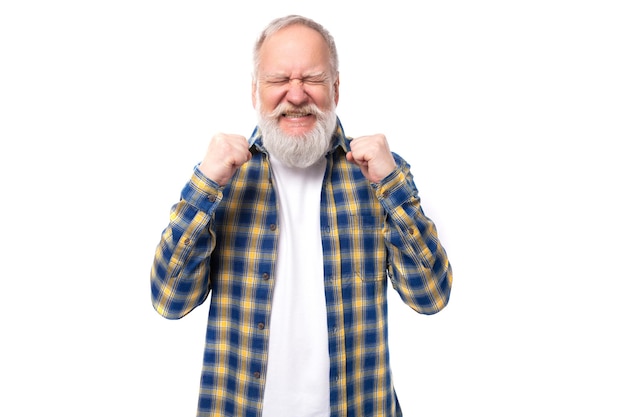 Senior pensioner grayhaired man with a beard in a shirt dreams covering his eyes on a white