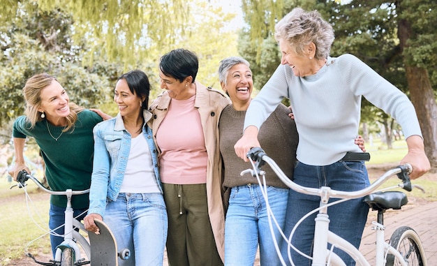 Senior people friends and laughing on bike in joyful happiness enjoying fun time together at the park Group of elderly women bonding and sharing joke laugh or walking and cycling in the outdoors