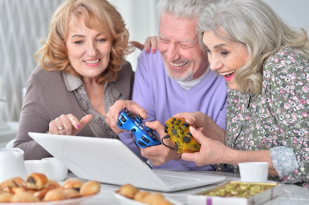 Senior people playing computer game with laptop while drinking t