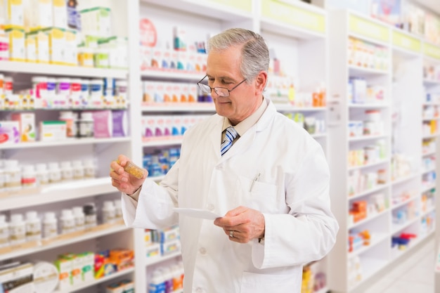 Senior pharmacist looking at medicine and prescription 